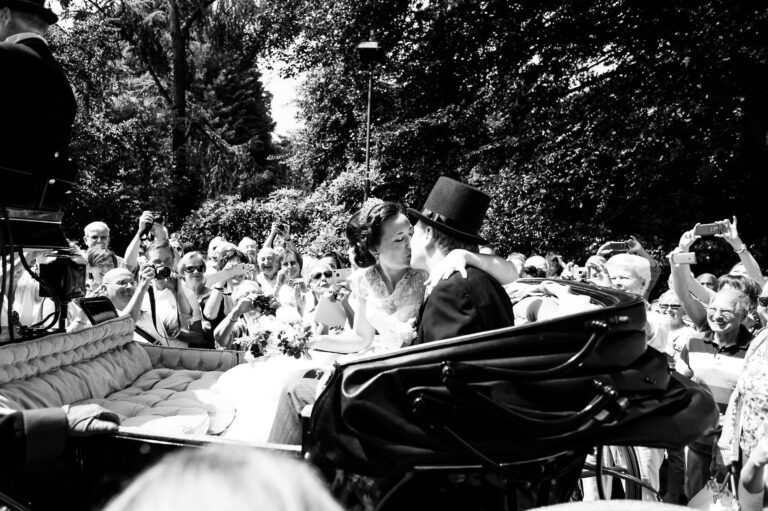 bride and groom kiss in horse drawn carriage