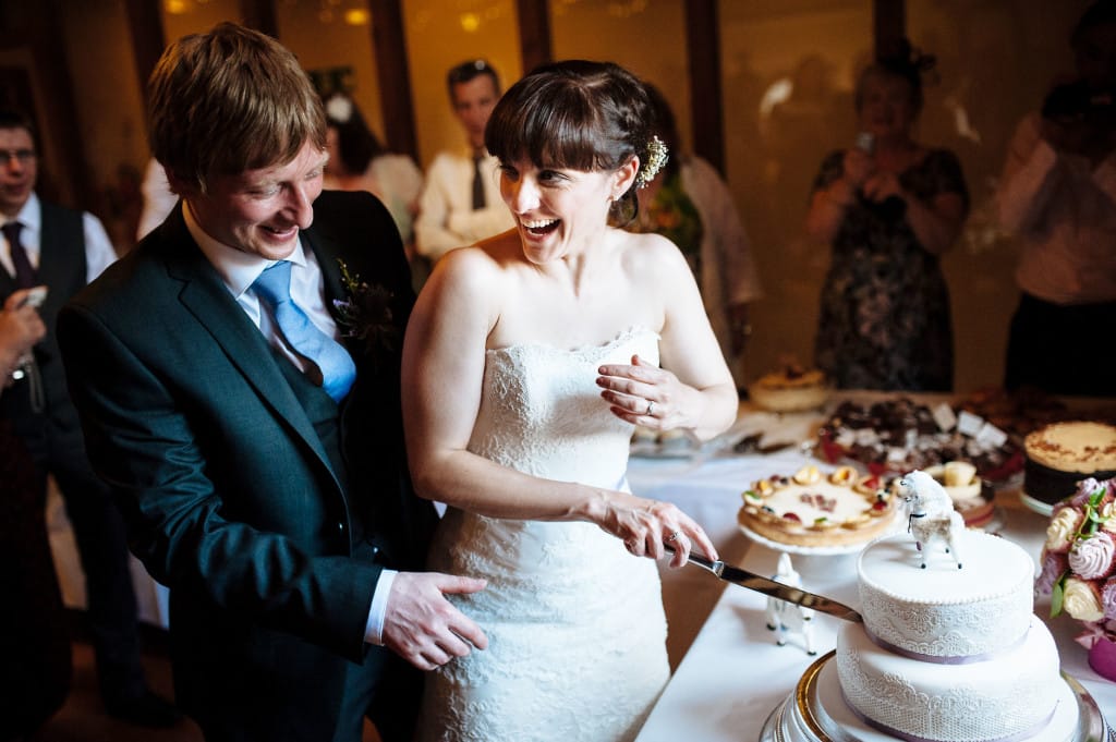 laughing bride and groom cutting the cake