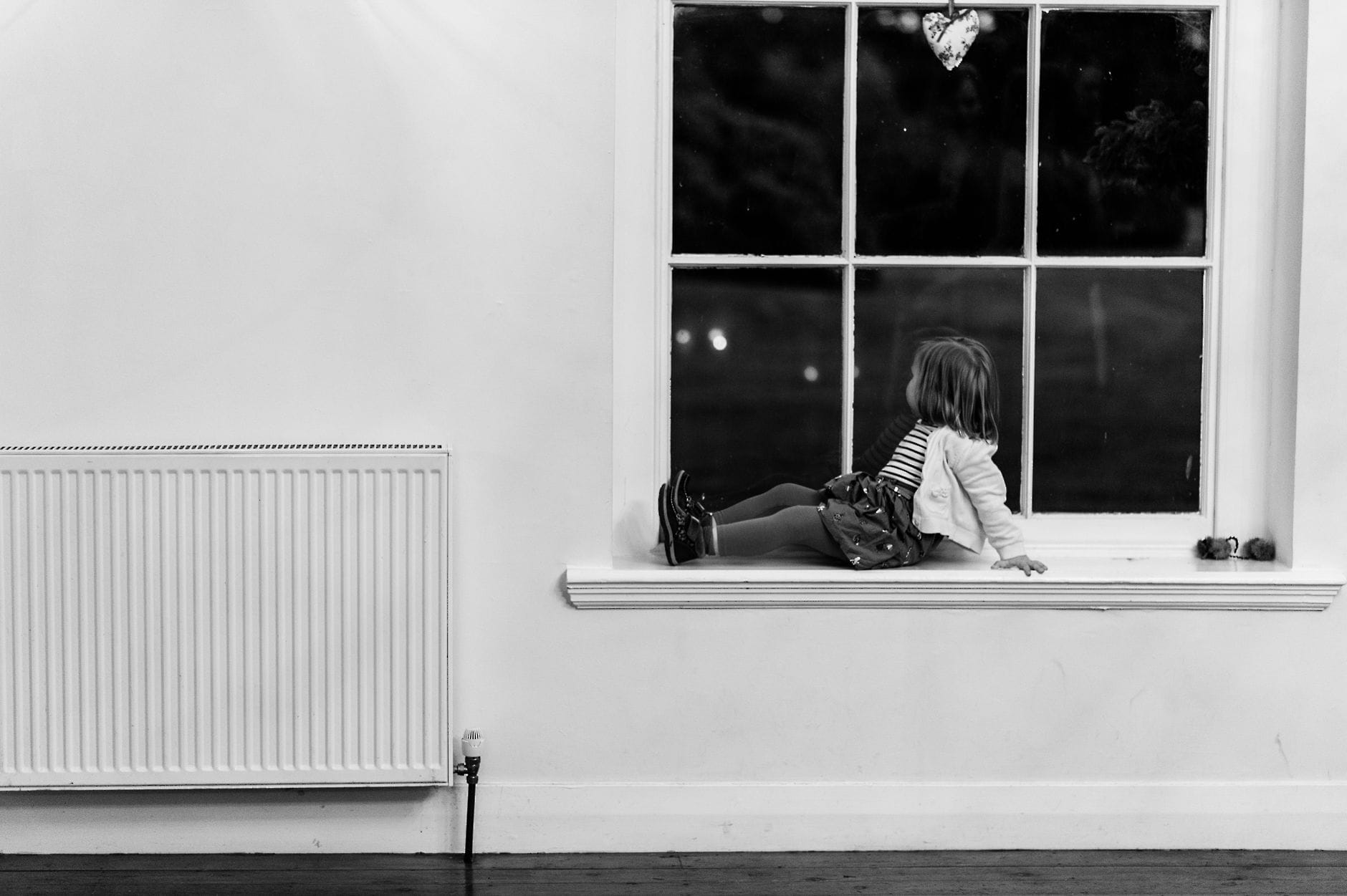 little girl sat on a windowsill looking outside