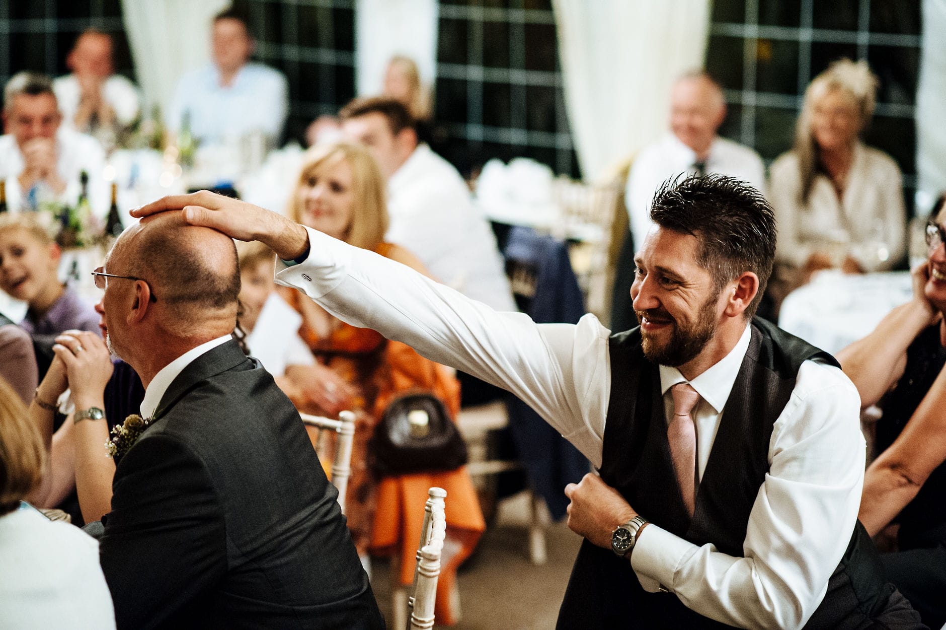 balding man having his head patted by a friend