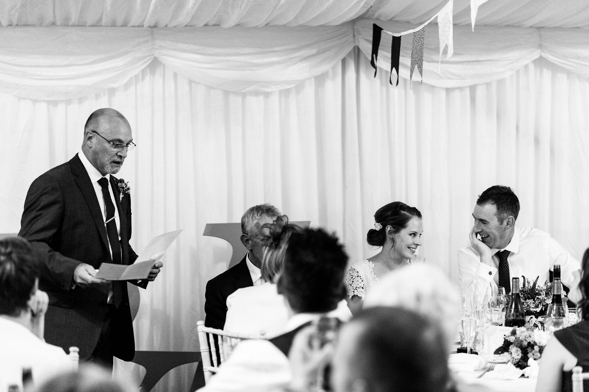 newlyweds smiling at each other during speeches