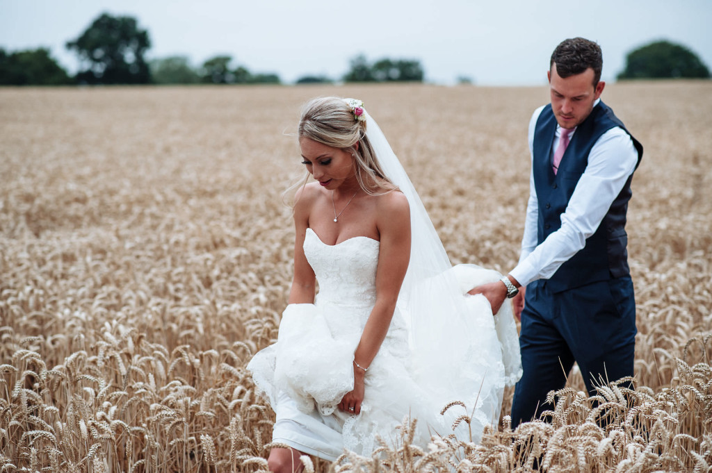 Bride and groom walking through corn field