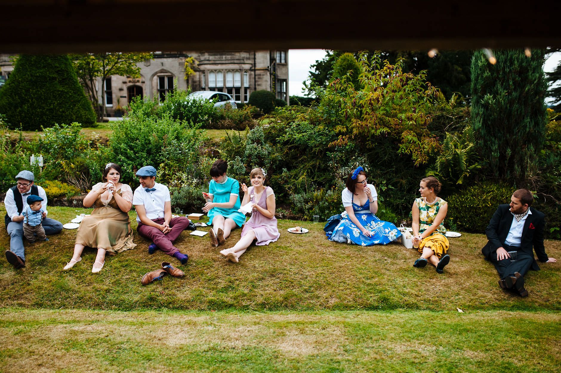 guests in vintage dress sat on a grass bank