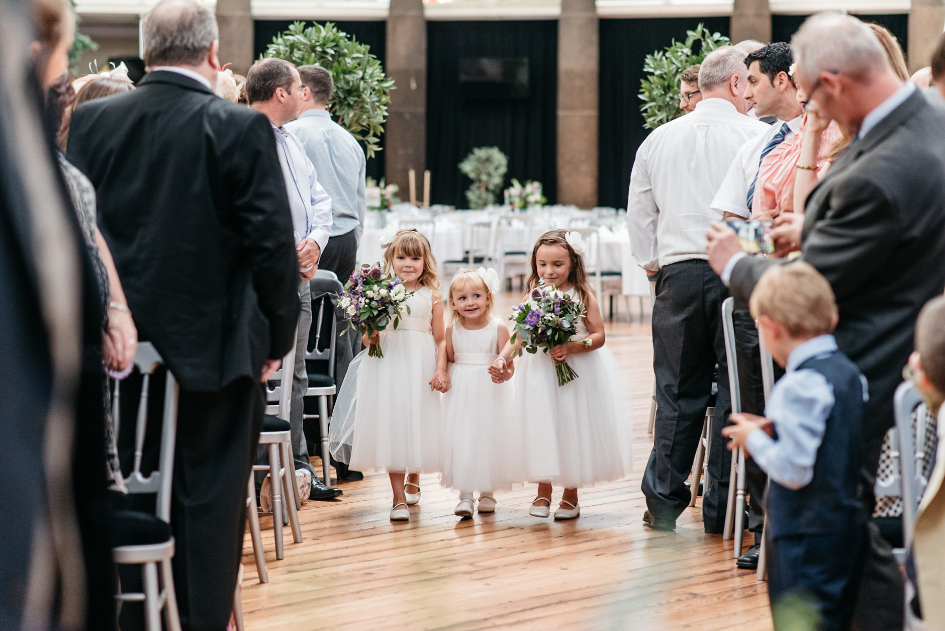 three cute flower girls walking down the aisle