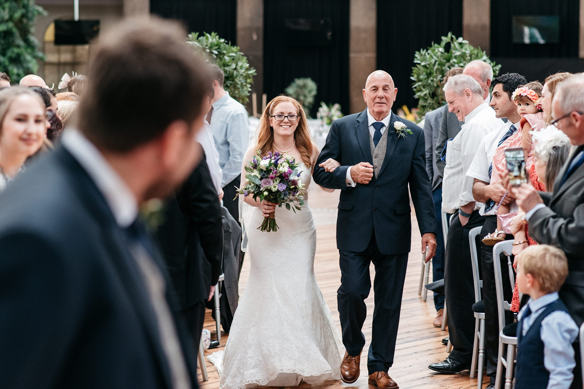 bride walks down the aisle with proud father