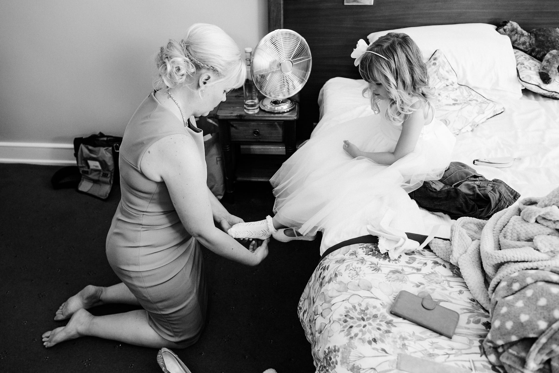 mum puts flower girls shoes on