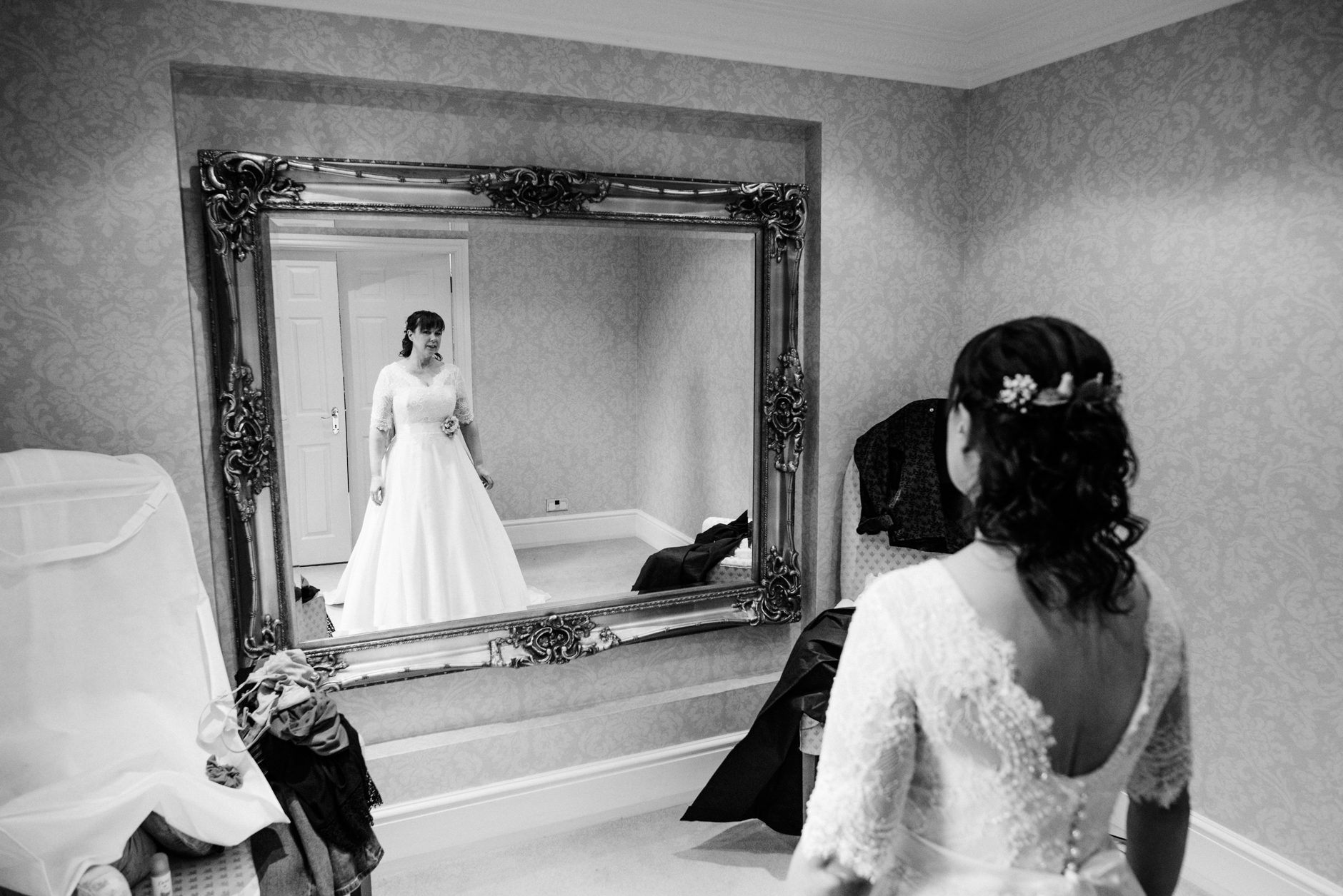 bride in her dress in front of a large mirror