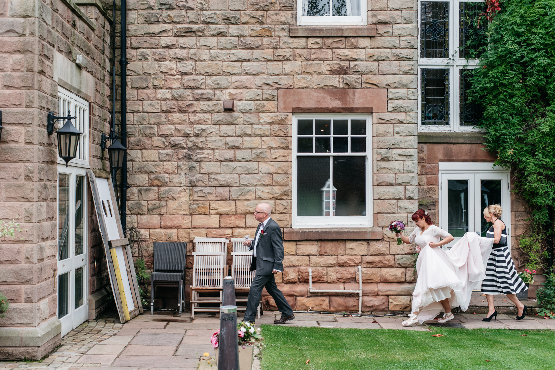 bridesmaid holding dress as bride walks