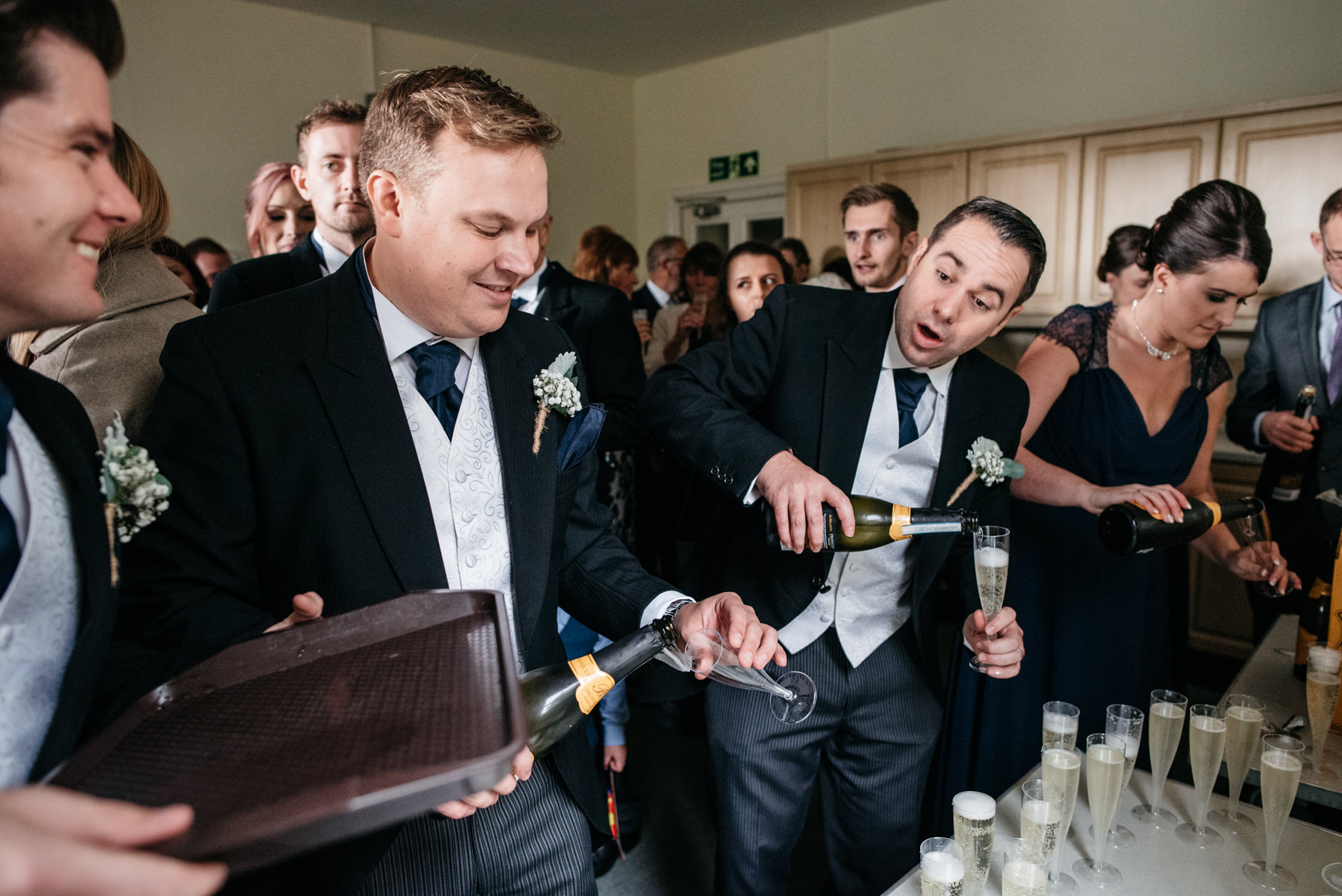 Groomsmen pouring champagne for guests