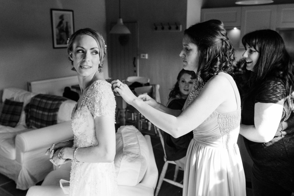 bridesmaid helping bride with her dress