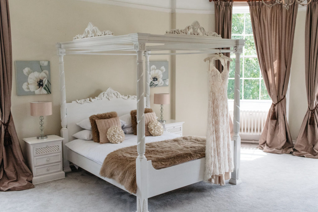 wedding dress hanging on four poster bed