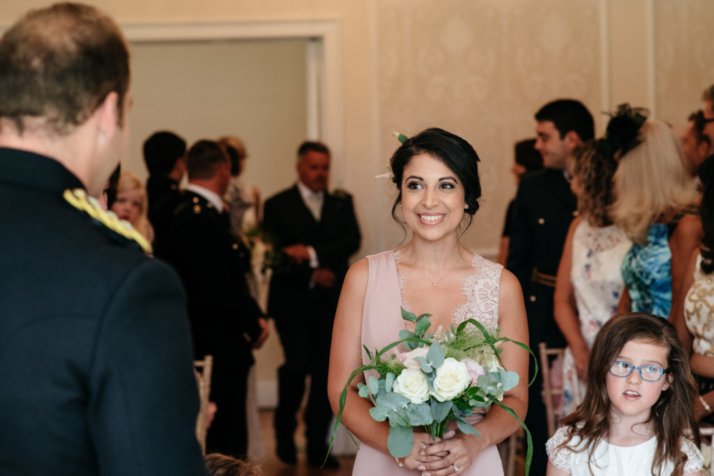 smiling bridesmaid walks down the aisle