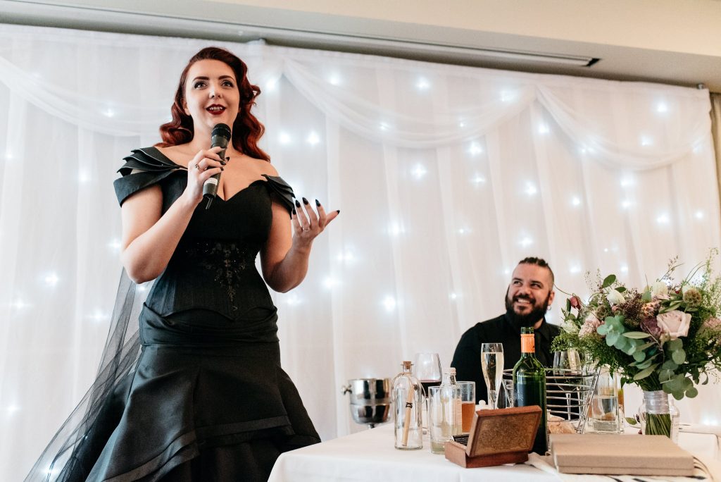 bride giving a speech wearing a black dress