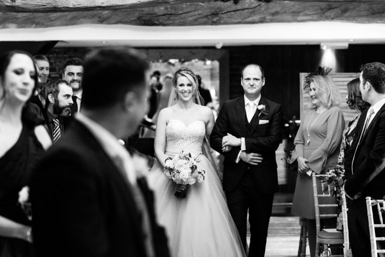black and white photo of bride walking down the aisle