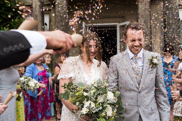 bride and groom walking through a confetti tunnel