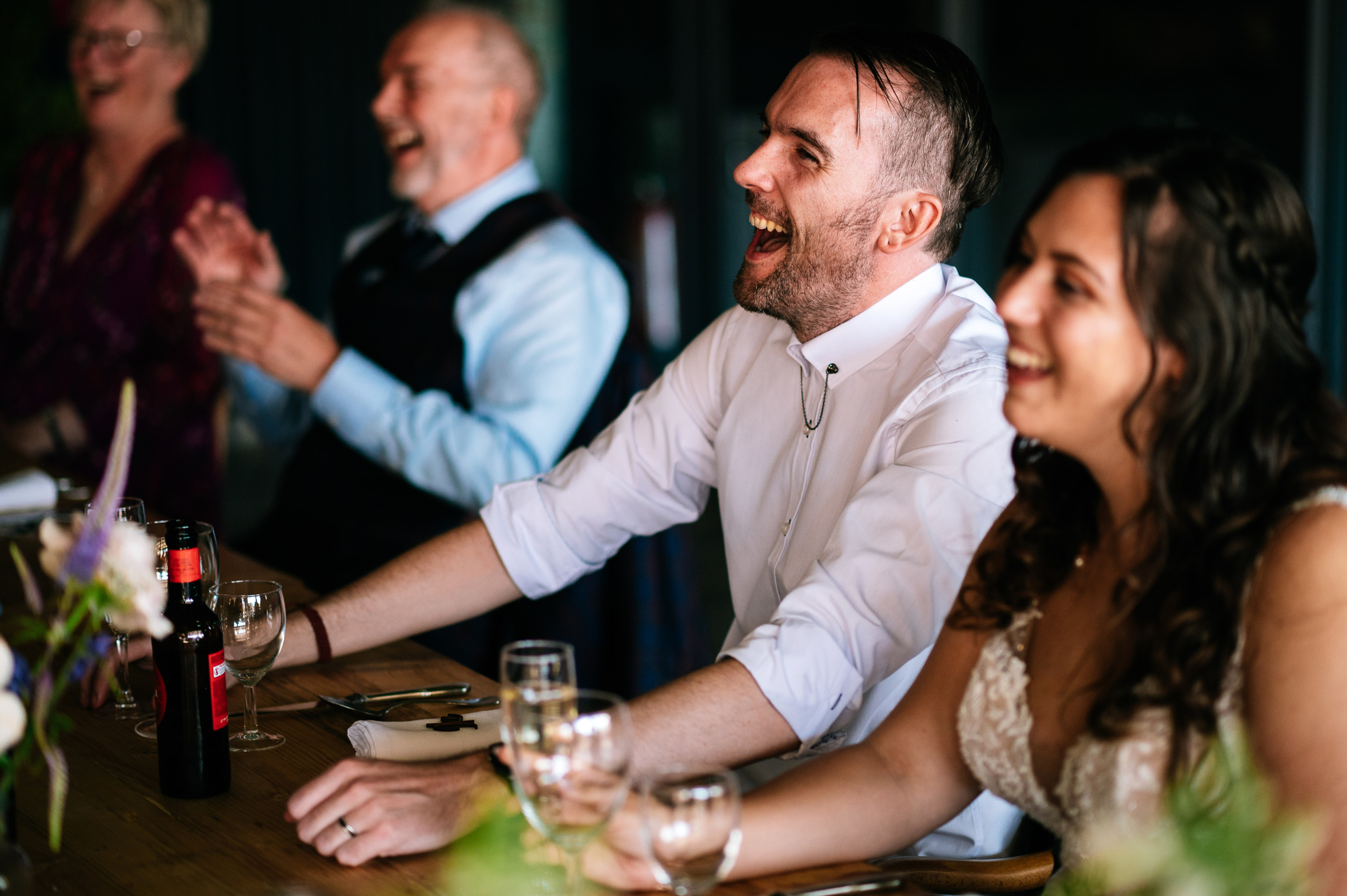bride and groom laughing during best man's speech