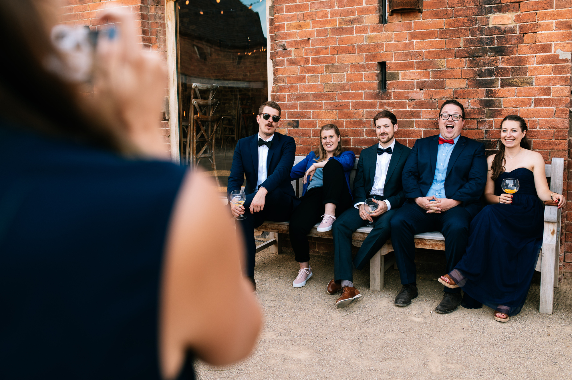 laughing guests posing for a photo sat on a bench