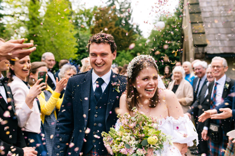 laughing couple walking through a confetti tunnel
