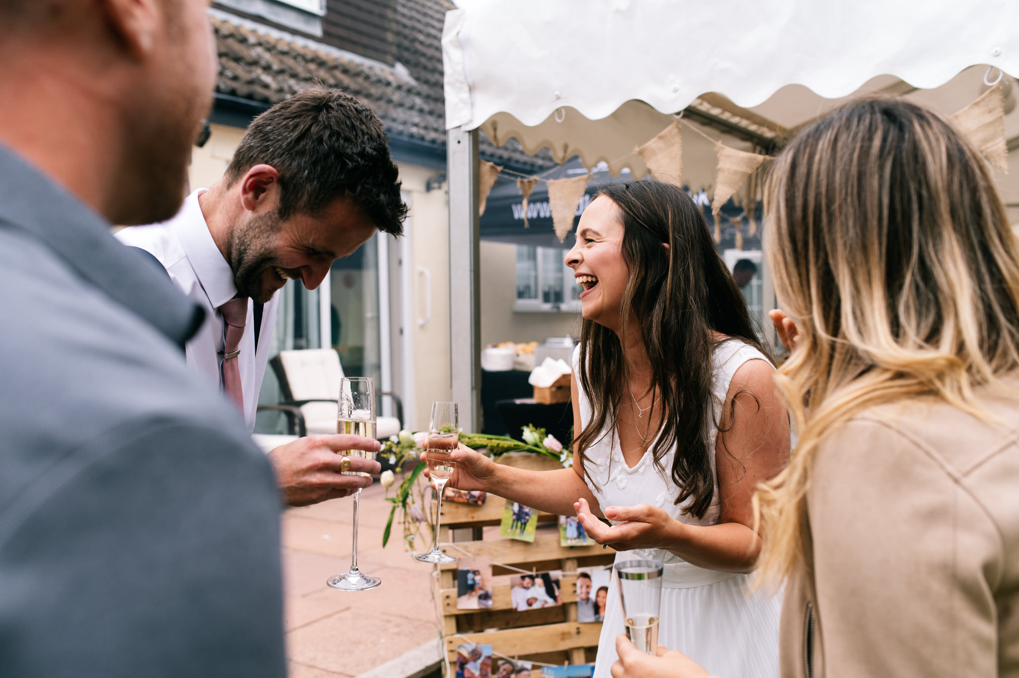 a bride and groom sharing a drink and a laugh with some friends at their garden wedding reception in nottinghamshire