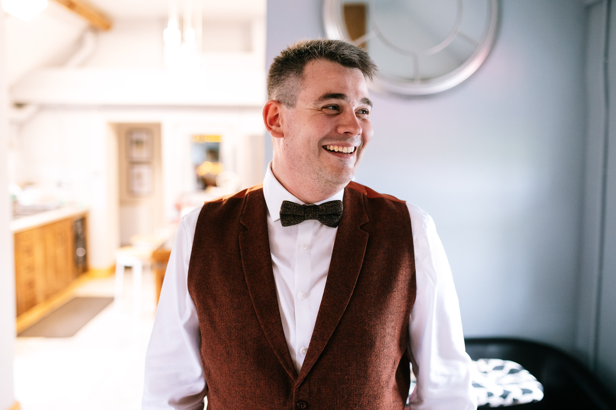 smiling groom wearing brown waistcoat and bow tie