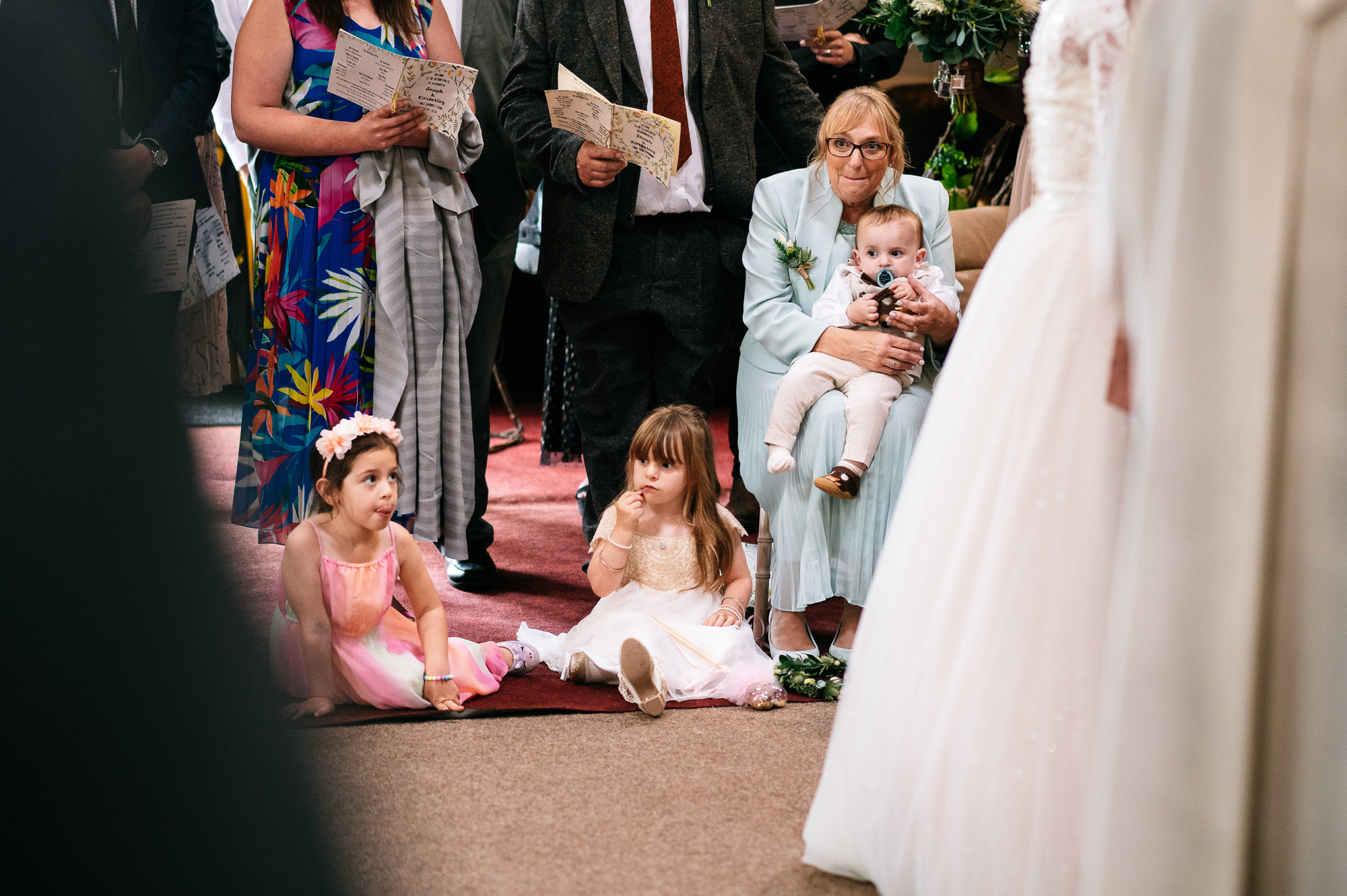 kids sat on the floor during a wedding ceremony
