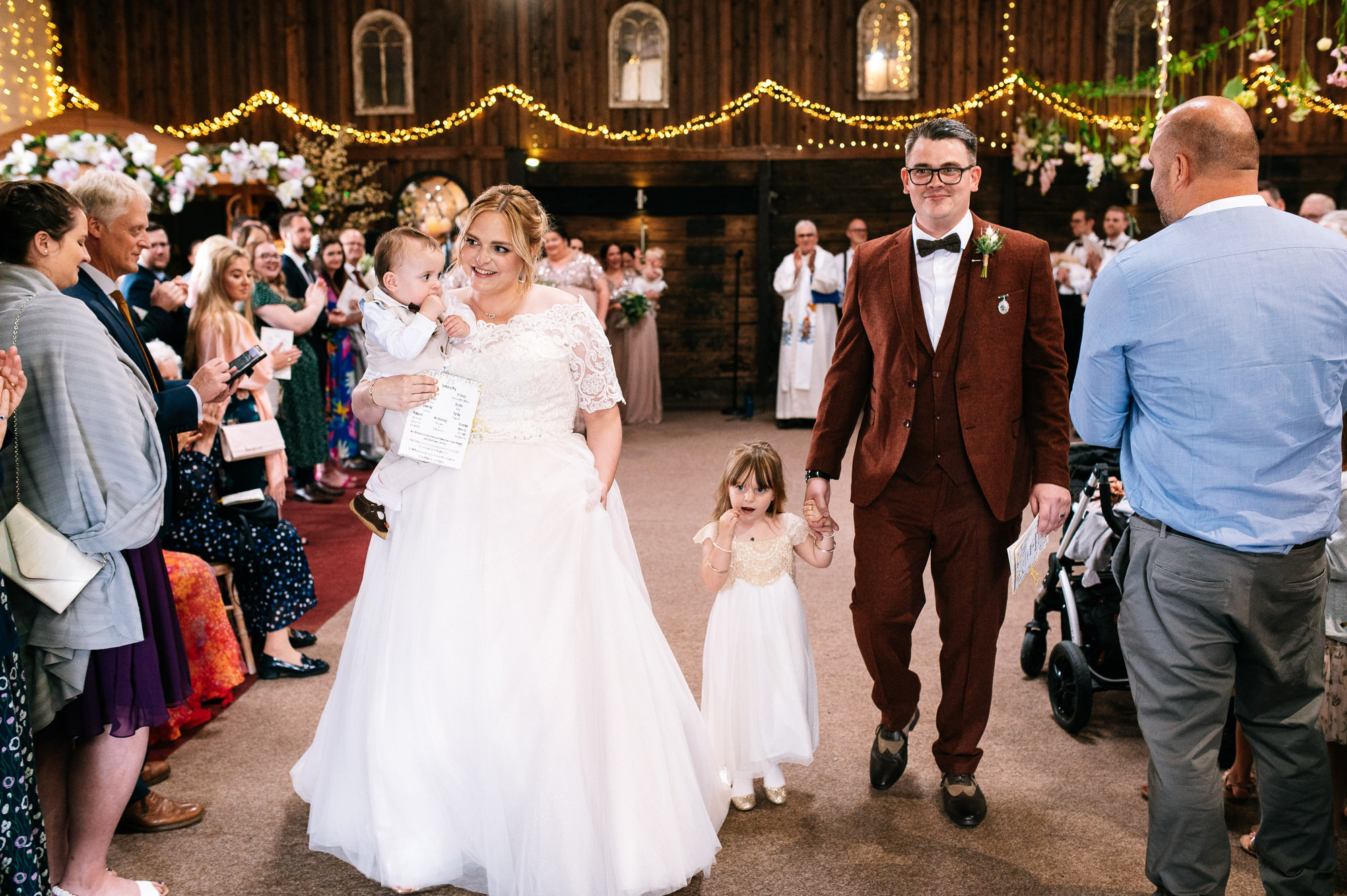 bride and groom walking down the aisle with their kids