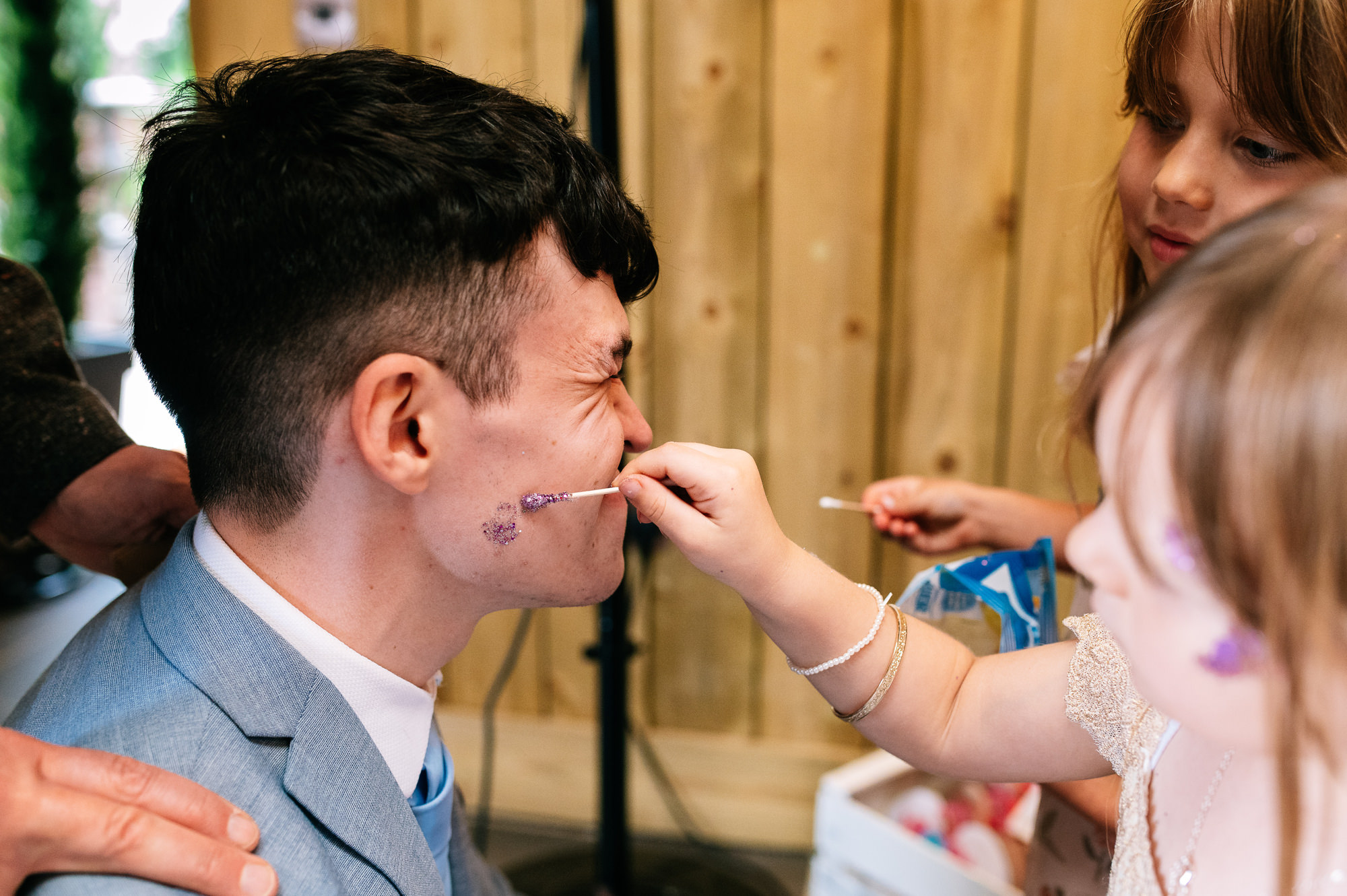 kids putting facepaint on a man's face