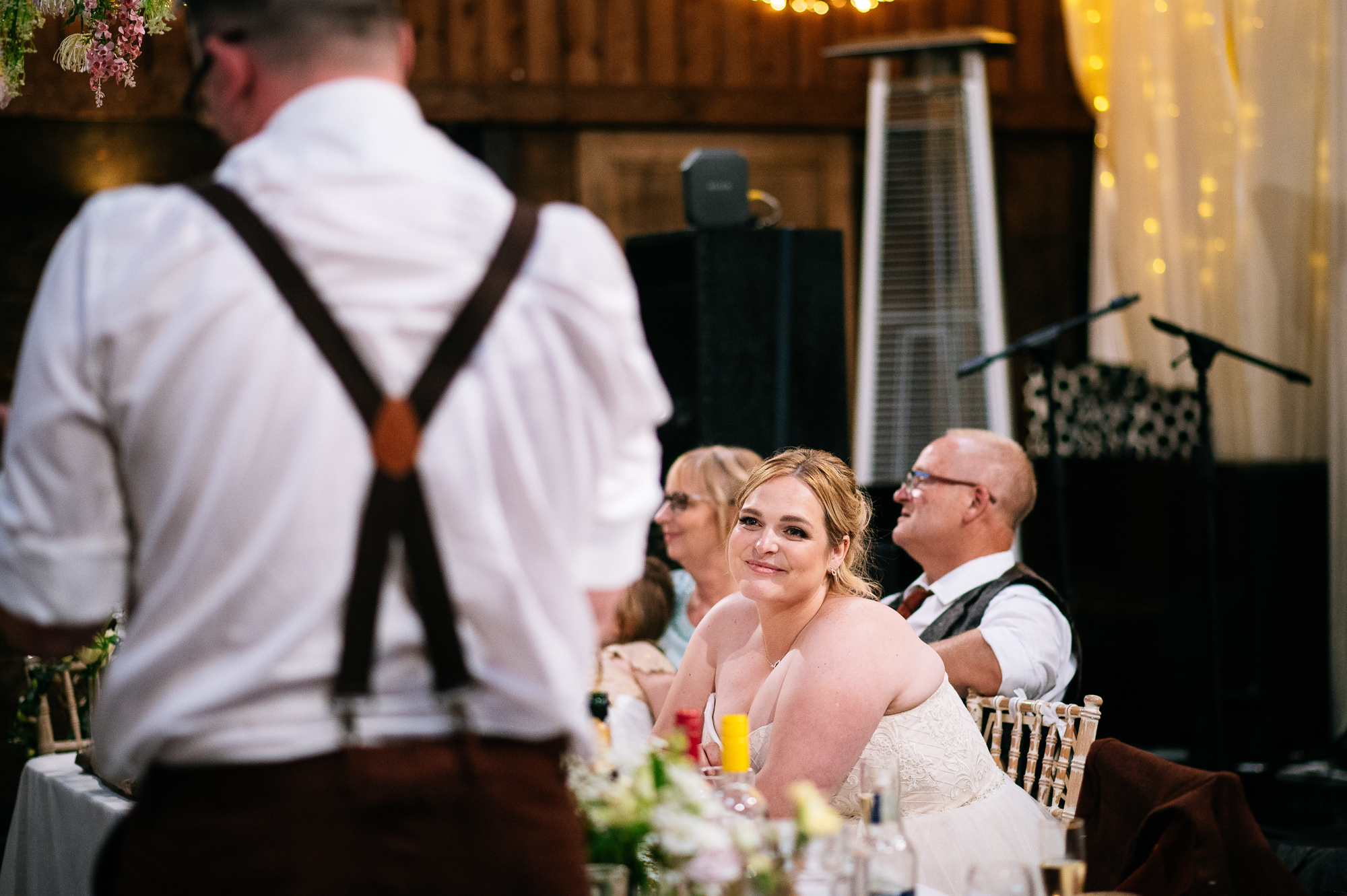 bride smiling at her husband during his speech