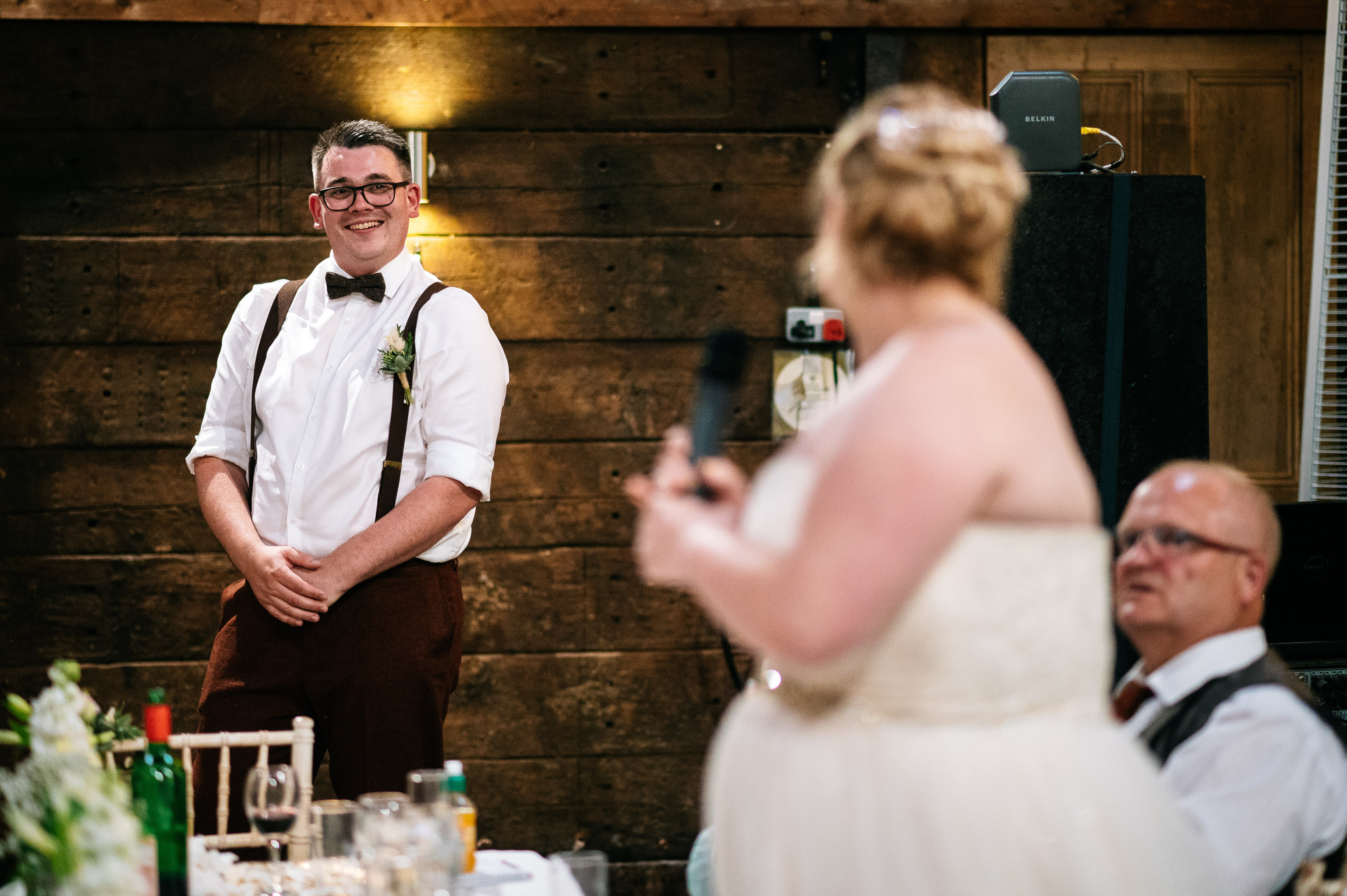 groom smiling at his wife during her speech