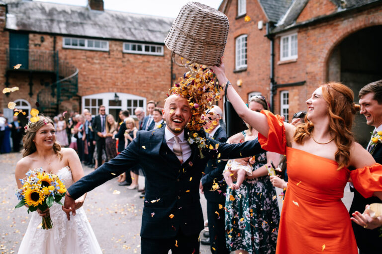 grooms sister dumping basket of confetti over his head