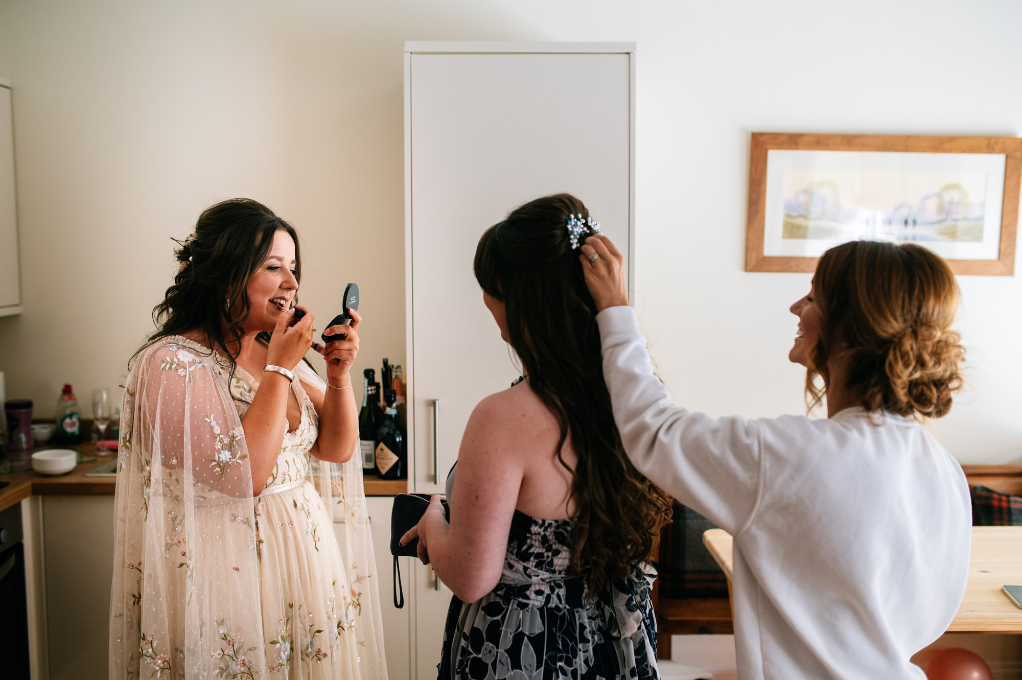 bride touching up her own makeup whilst wearing her wedding dress
