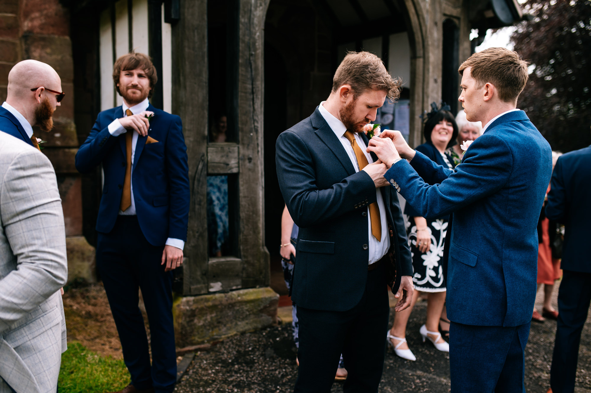 groom helping his groomsmen with their buttonholes