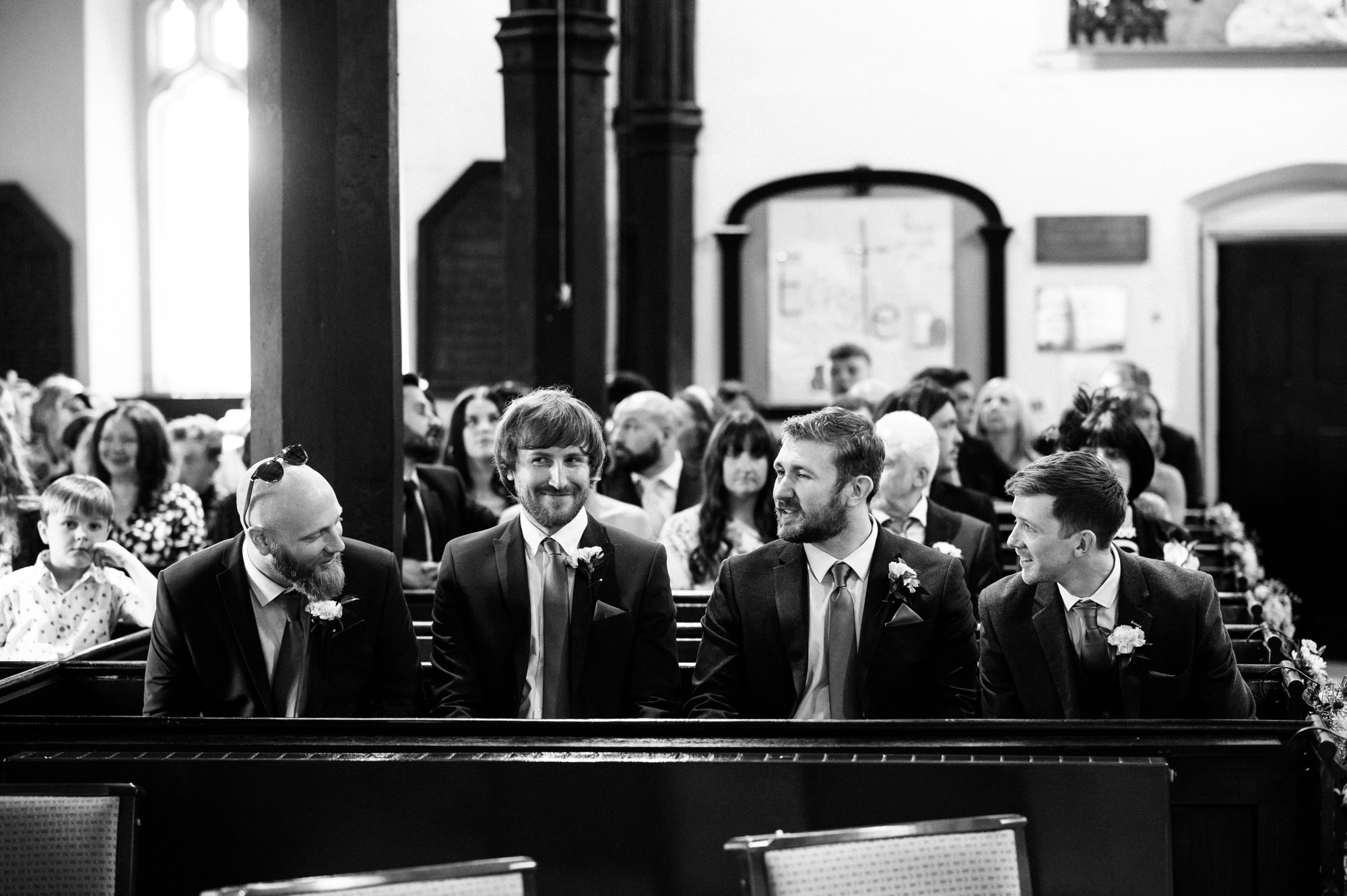 groom and groomsmen sat together at the front of the church
