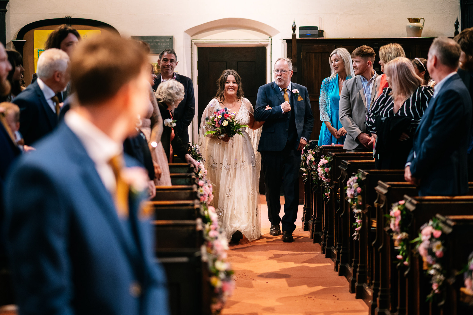 bride walking down the aisle with her dad at betley village church