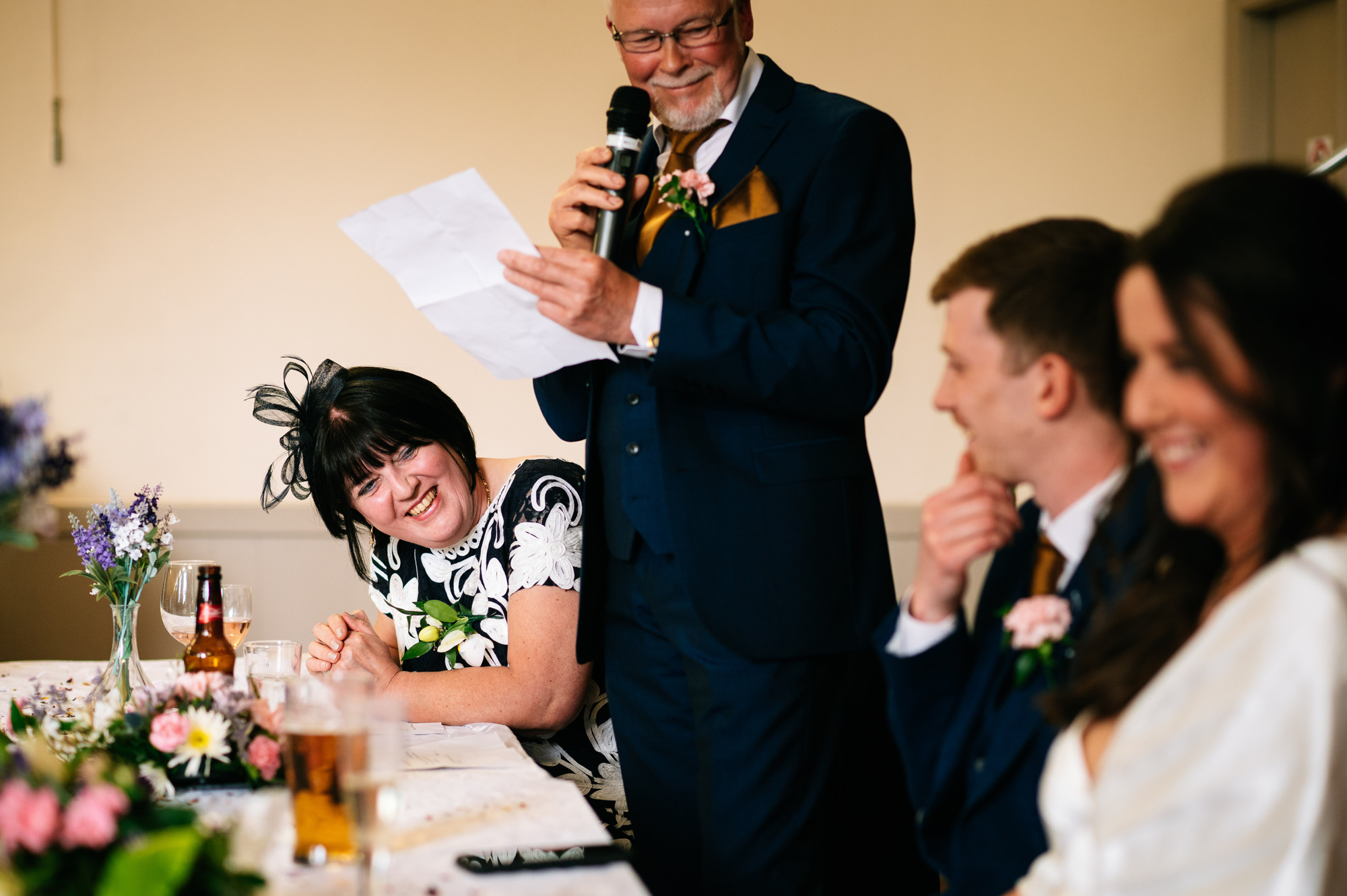 groom's mum looking over at her son during his dad's speech