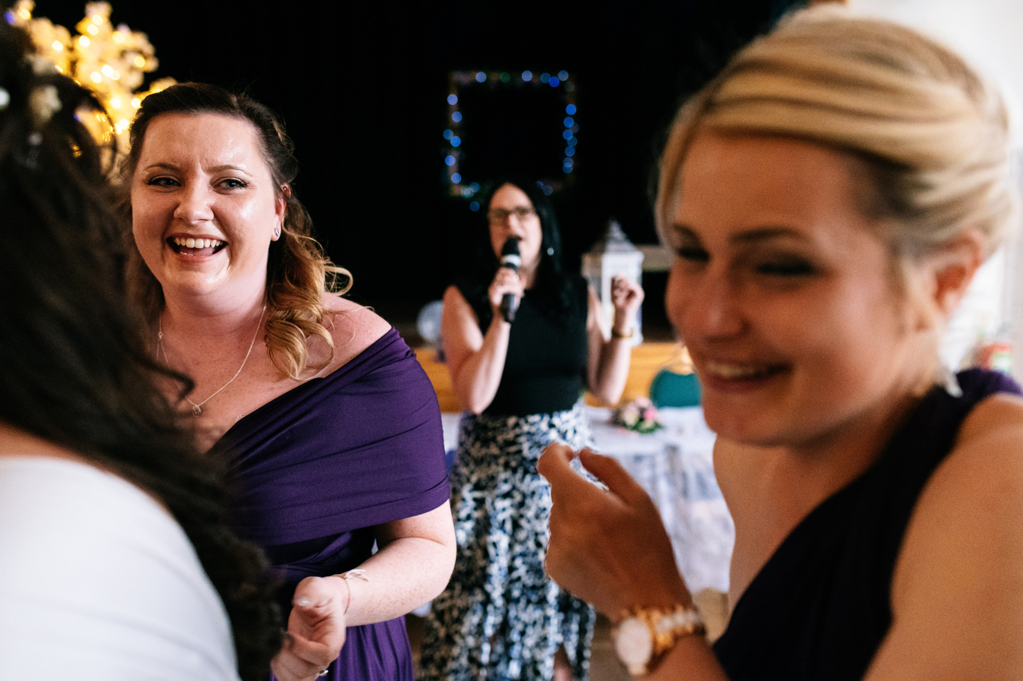 guests laughing while a lady is singing into the microphone