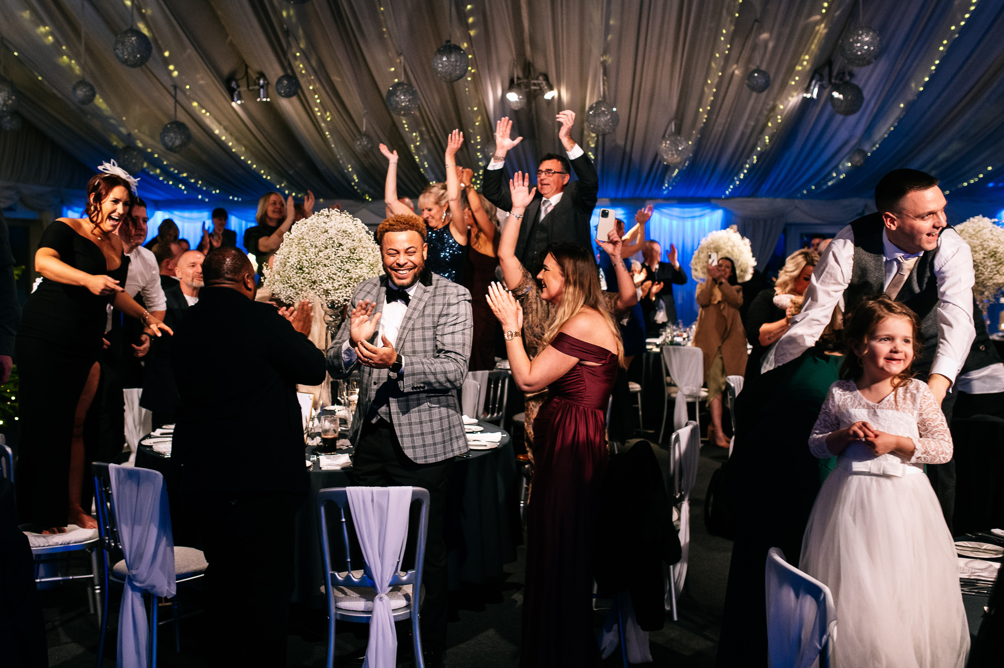 guests cheering as the couple enter their wedding breakfast