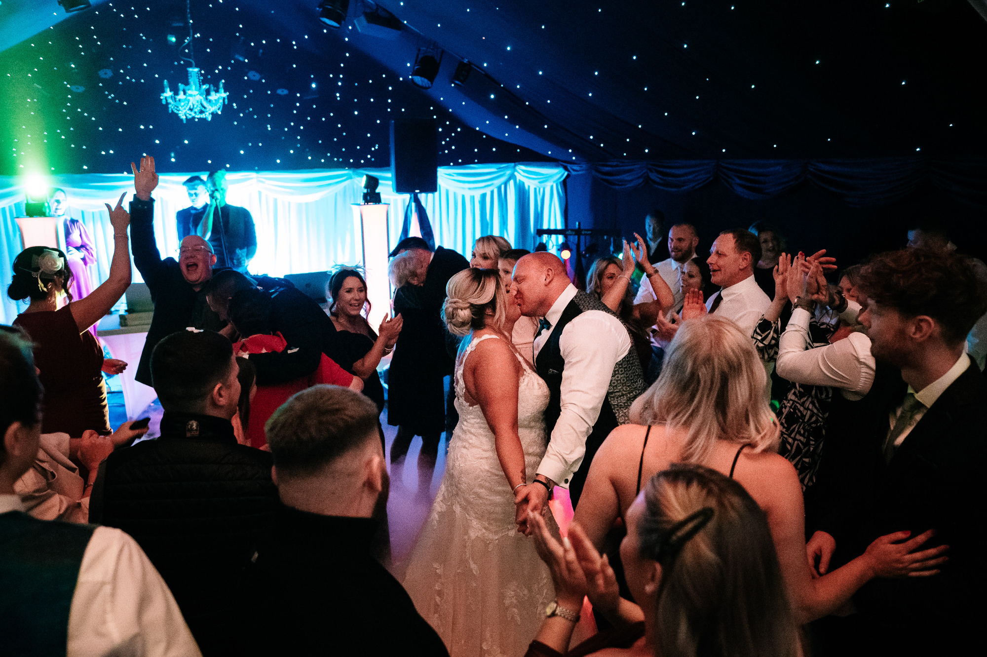bride and groom having a kiss on the dance floor surrounded by their guests