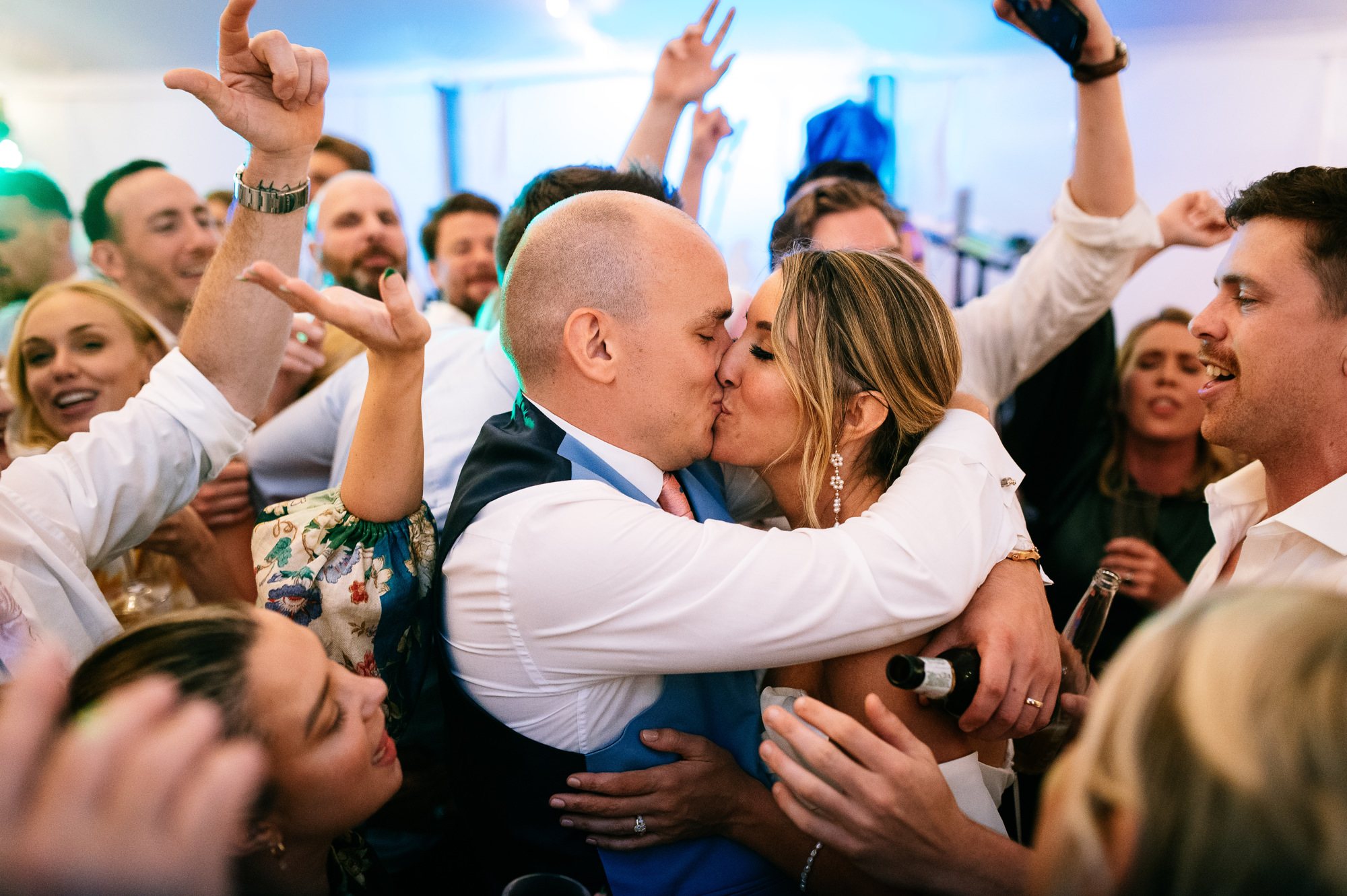 newlyweds kissing on the dance floor surrounded by their guests