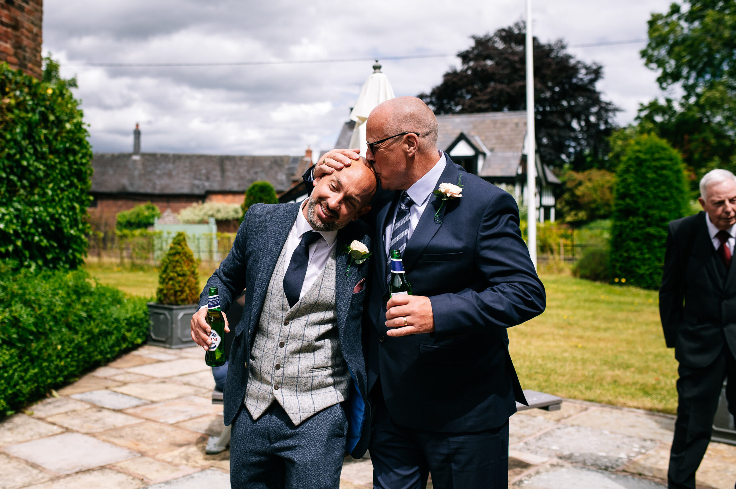 man kissing another mans bald head