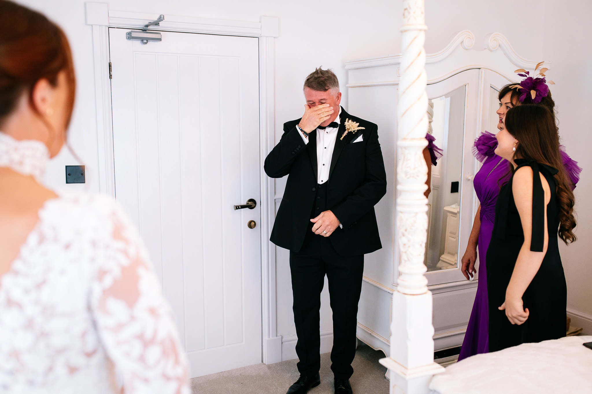 father of the bride wipes a tear away from his eye after seeing his daughter in her wedding dress