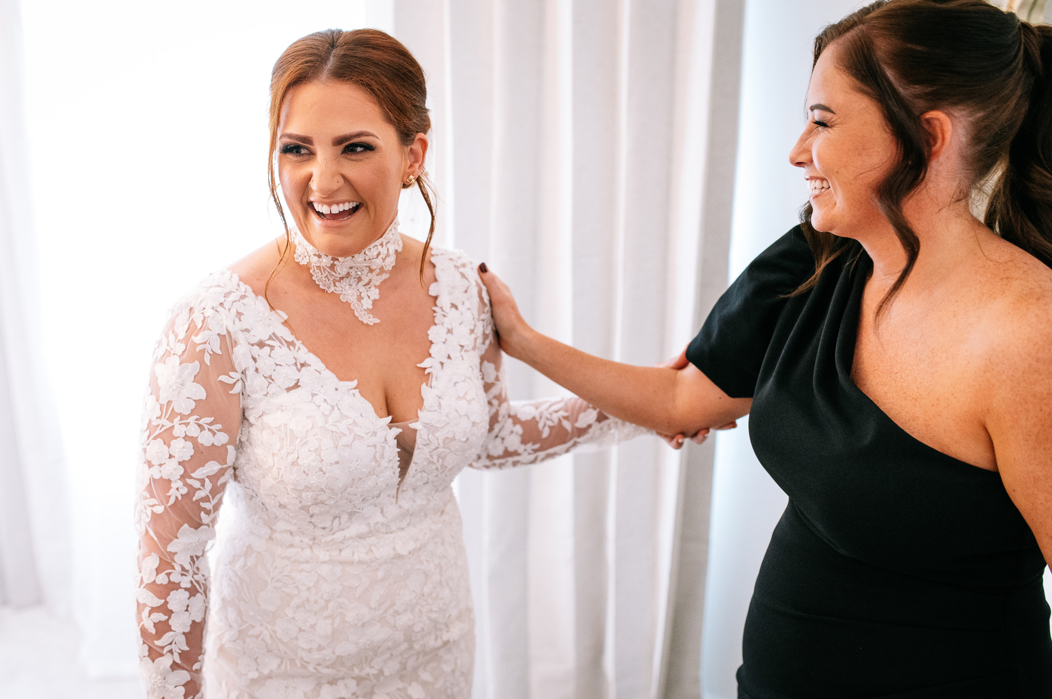 bride in her wedding dress with a bridesmaid laughing