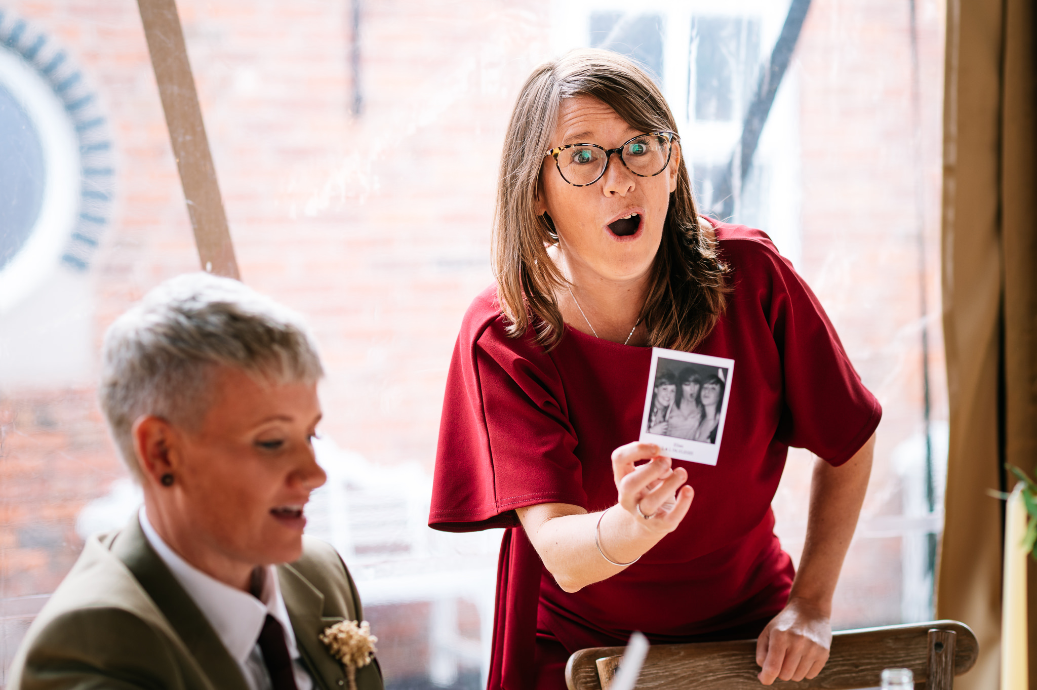 a woman holding up a photo with a shocked expression