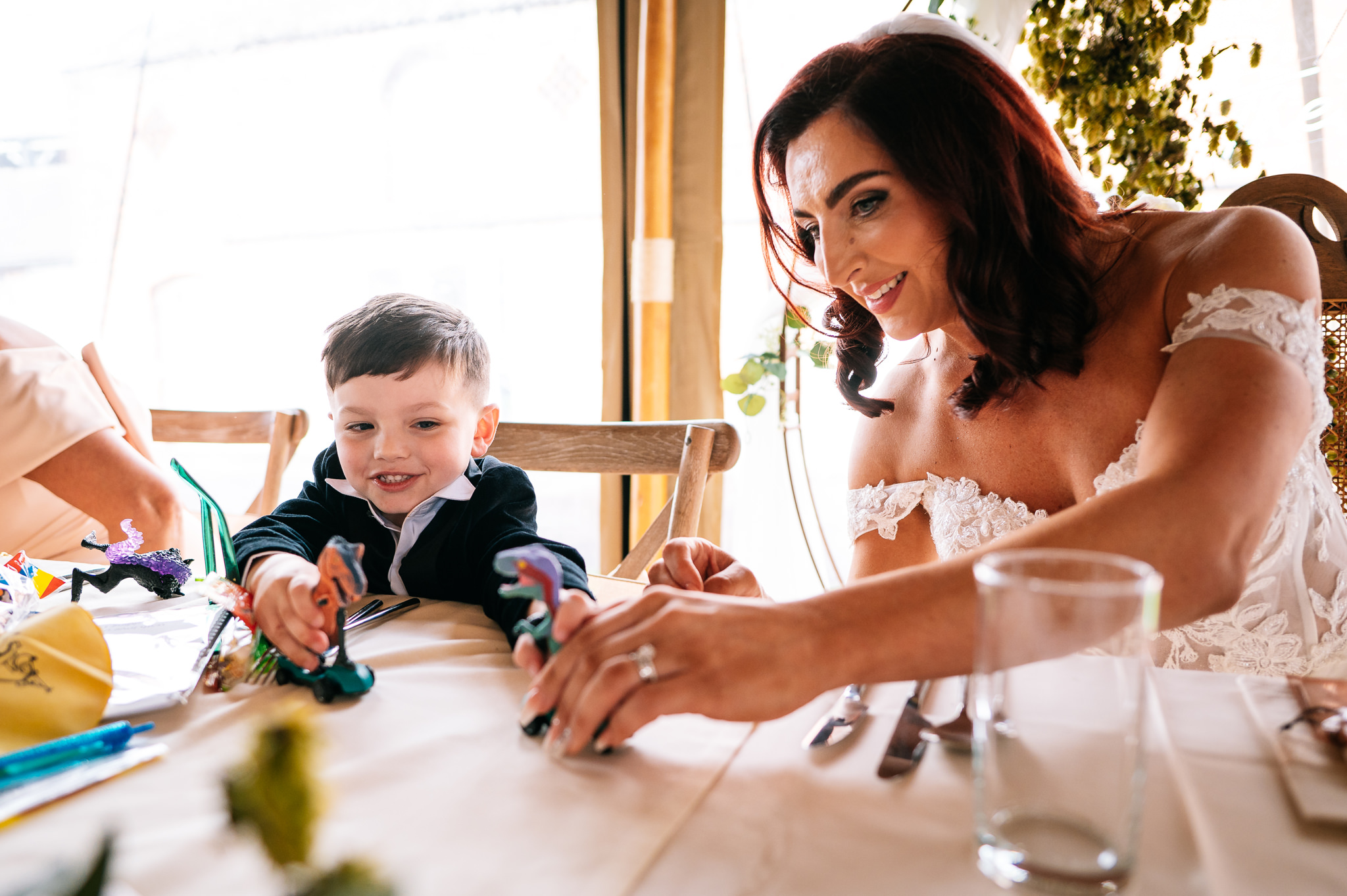 bride and her young son playing with toy dinosaurs at the top table