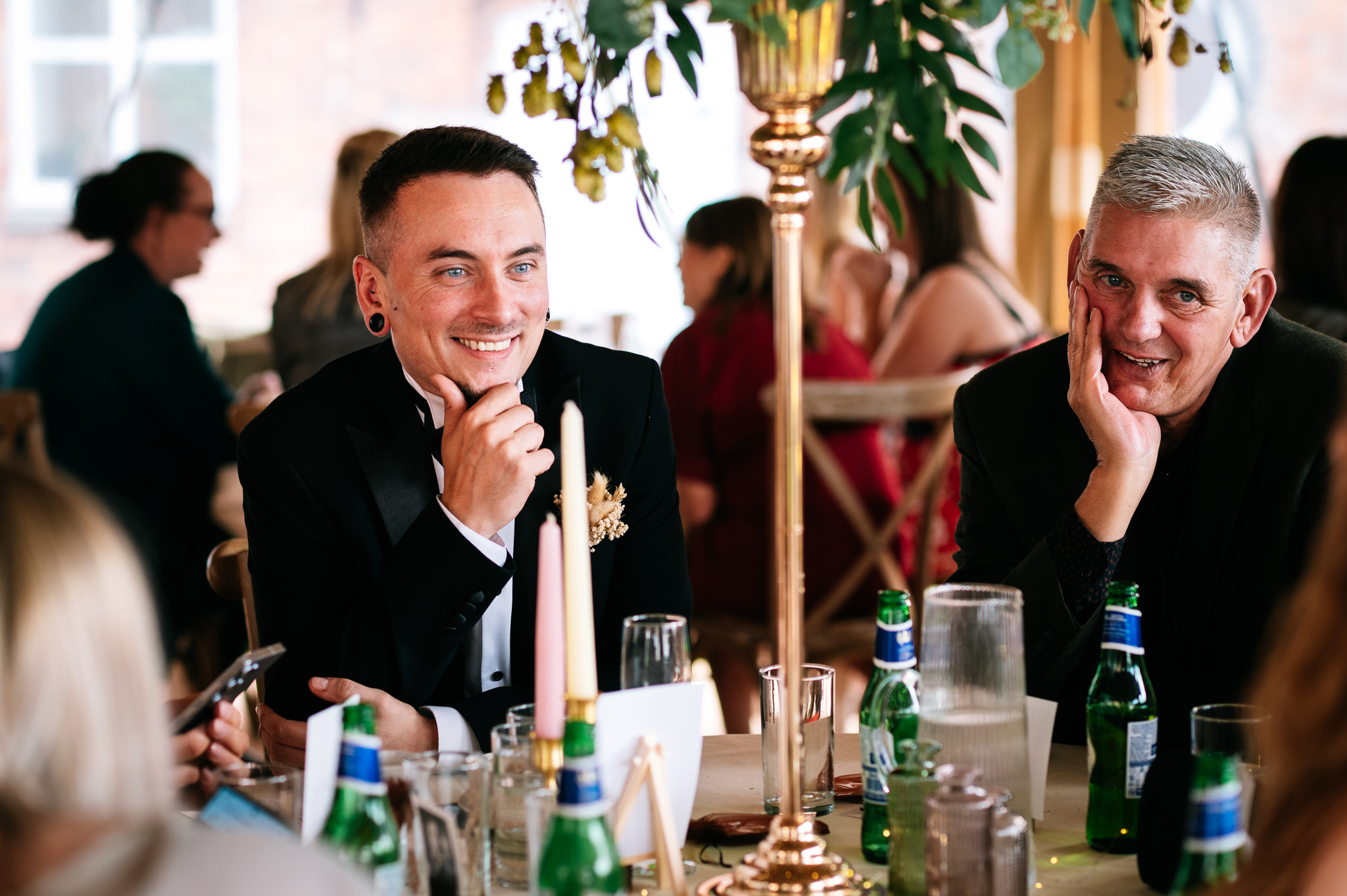 brother of the bride smiling as he chats to friends across the table