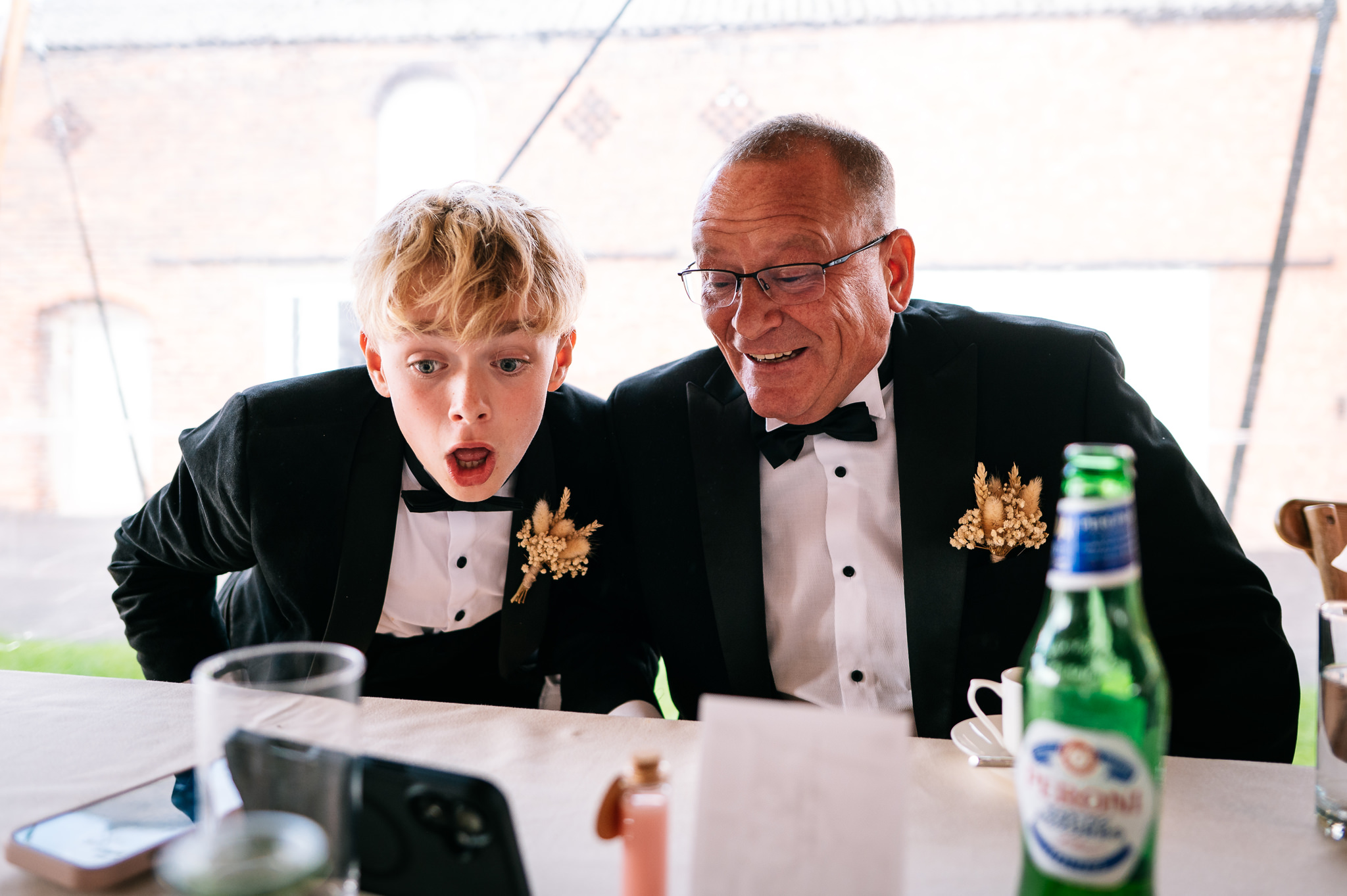 father of the bride and his grandson reacting to watching football on a phone