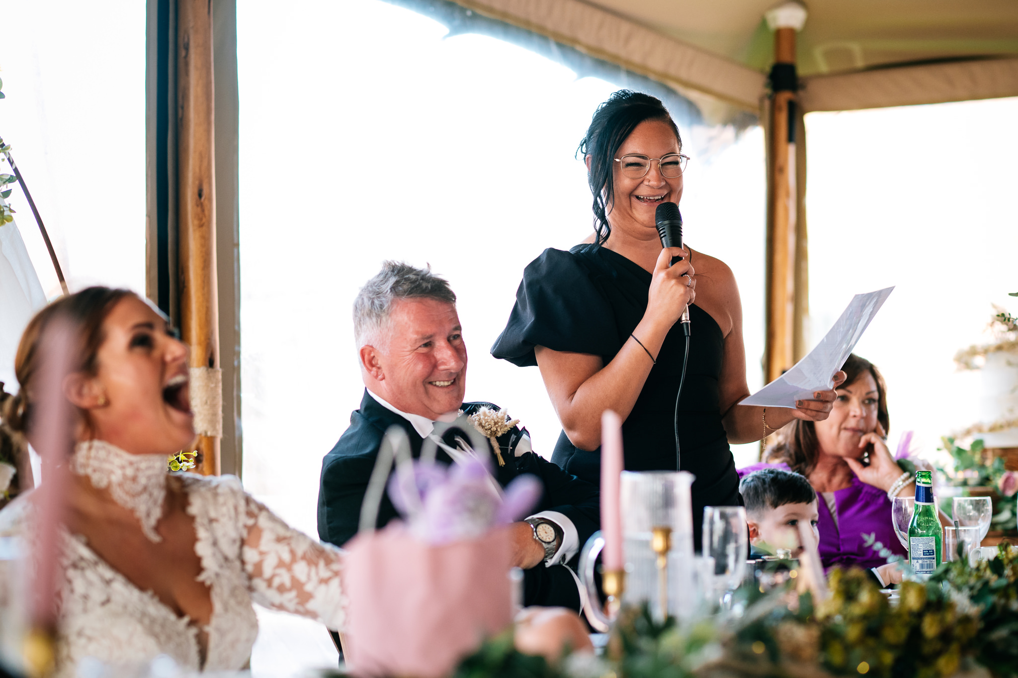 maid of honour giving a speech as the bride laughs in the foreground