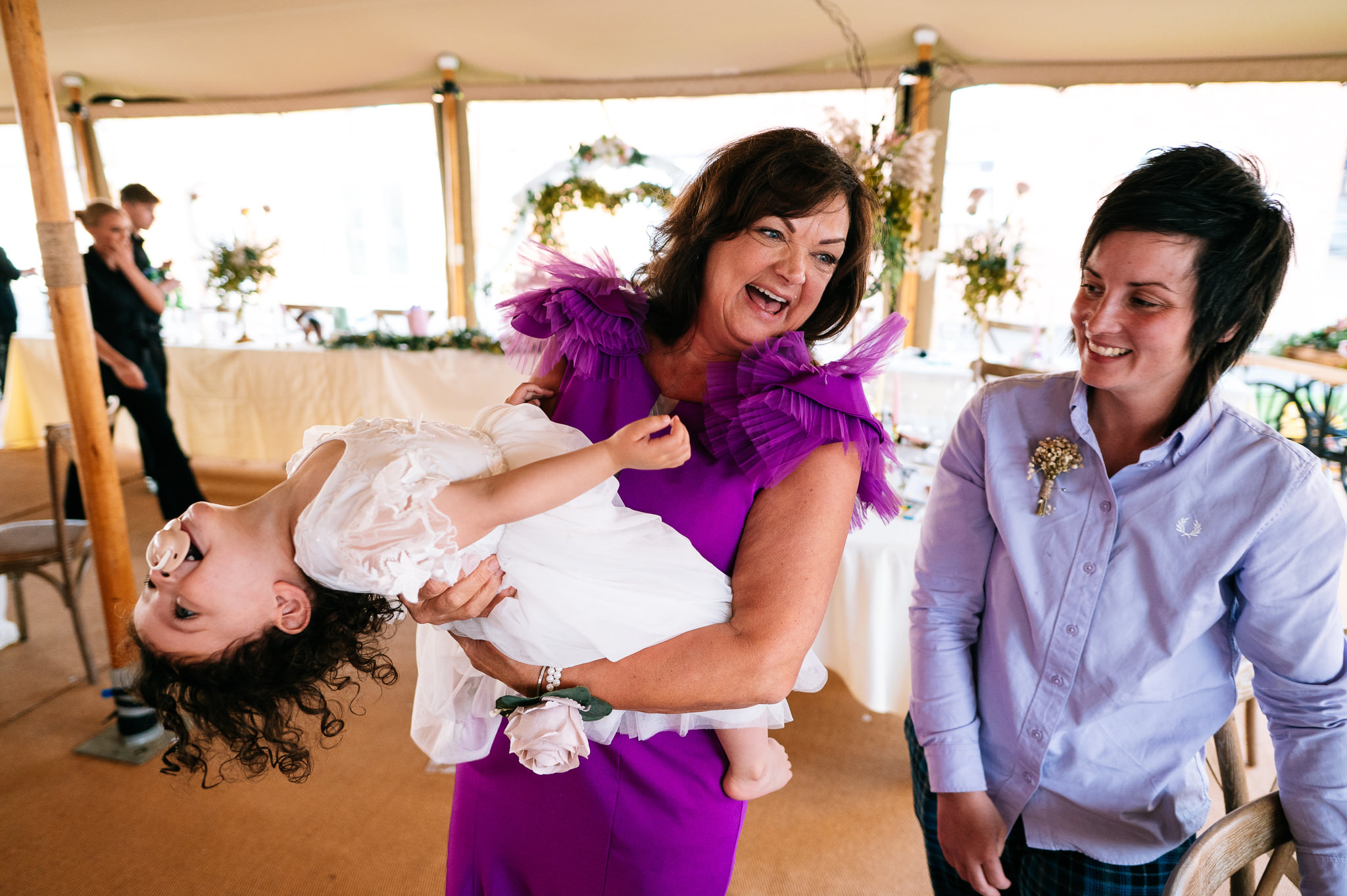 mother of the bride swinging her young granddaughter around and laughing