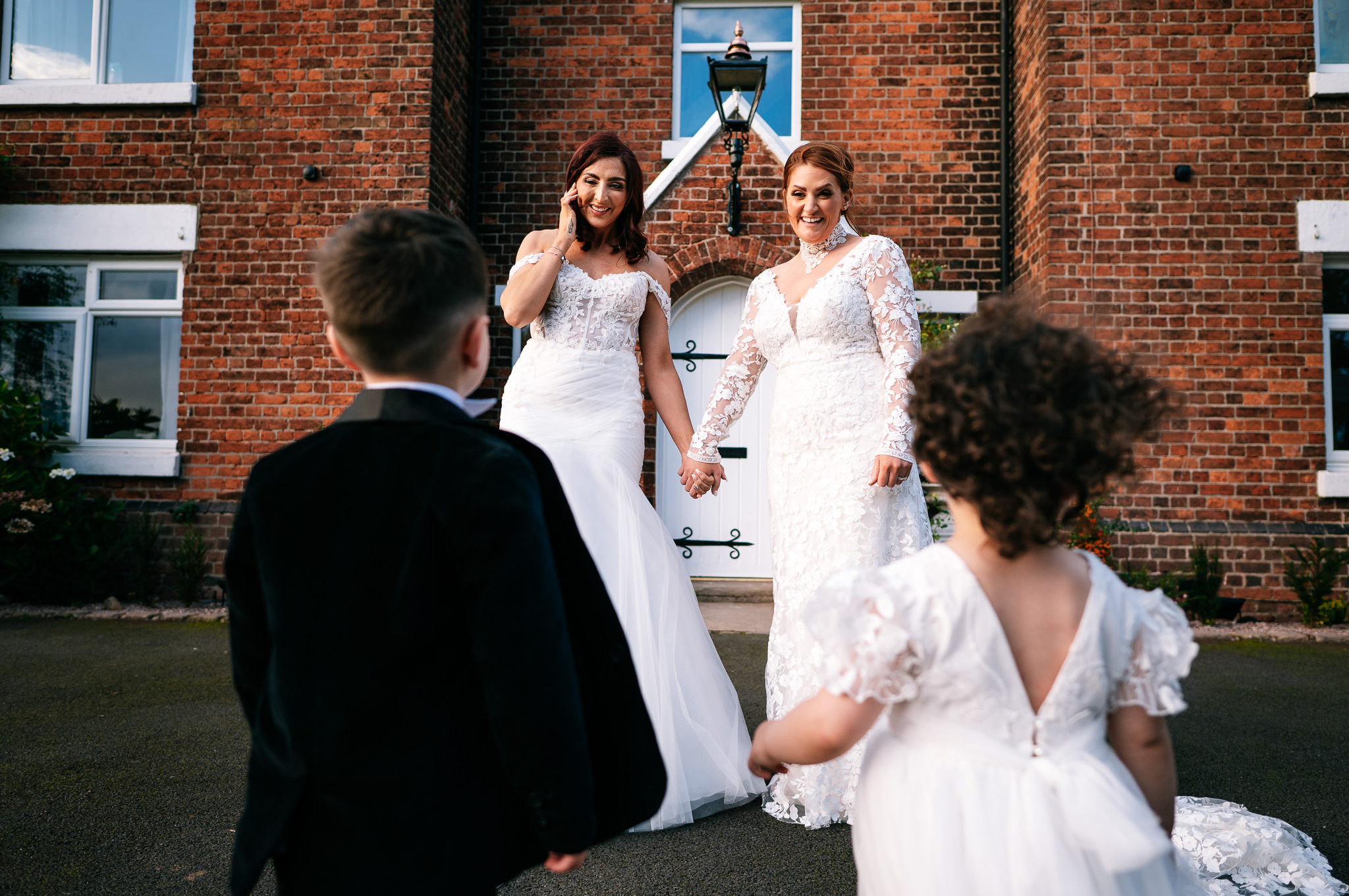 two brides stood smiling at their two young children