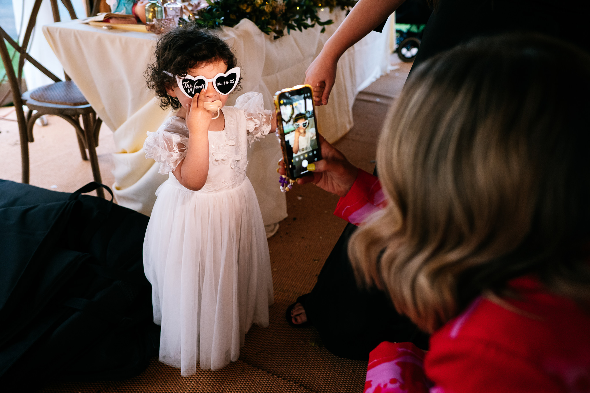 little bridesmaid in a white dress wearing wedding sunglasses posing for a photo